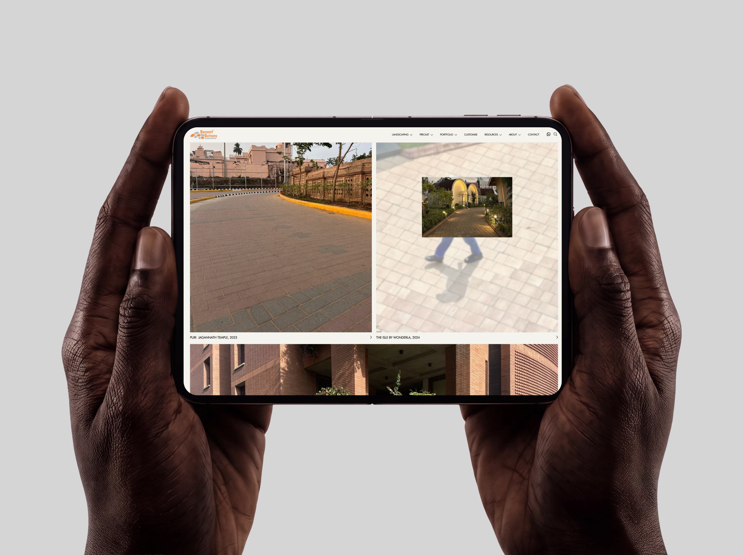 Basant Betons website on a tablet held in two hands, open on the project gallery.